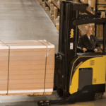A Yale narrow aisle forklift transporting goods between pallet racks in a warehouse.