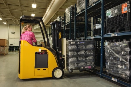 A Yale forklift picking a pallet of goods from a shelf in a warehouse.